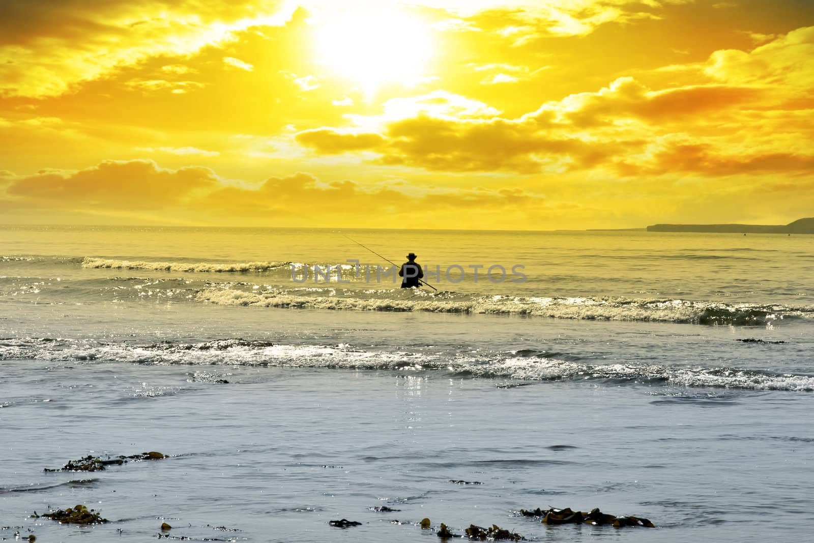 man fishing among the waves of the Atlantic ocean in Ballybunion county Kerry Ireland