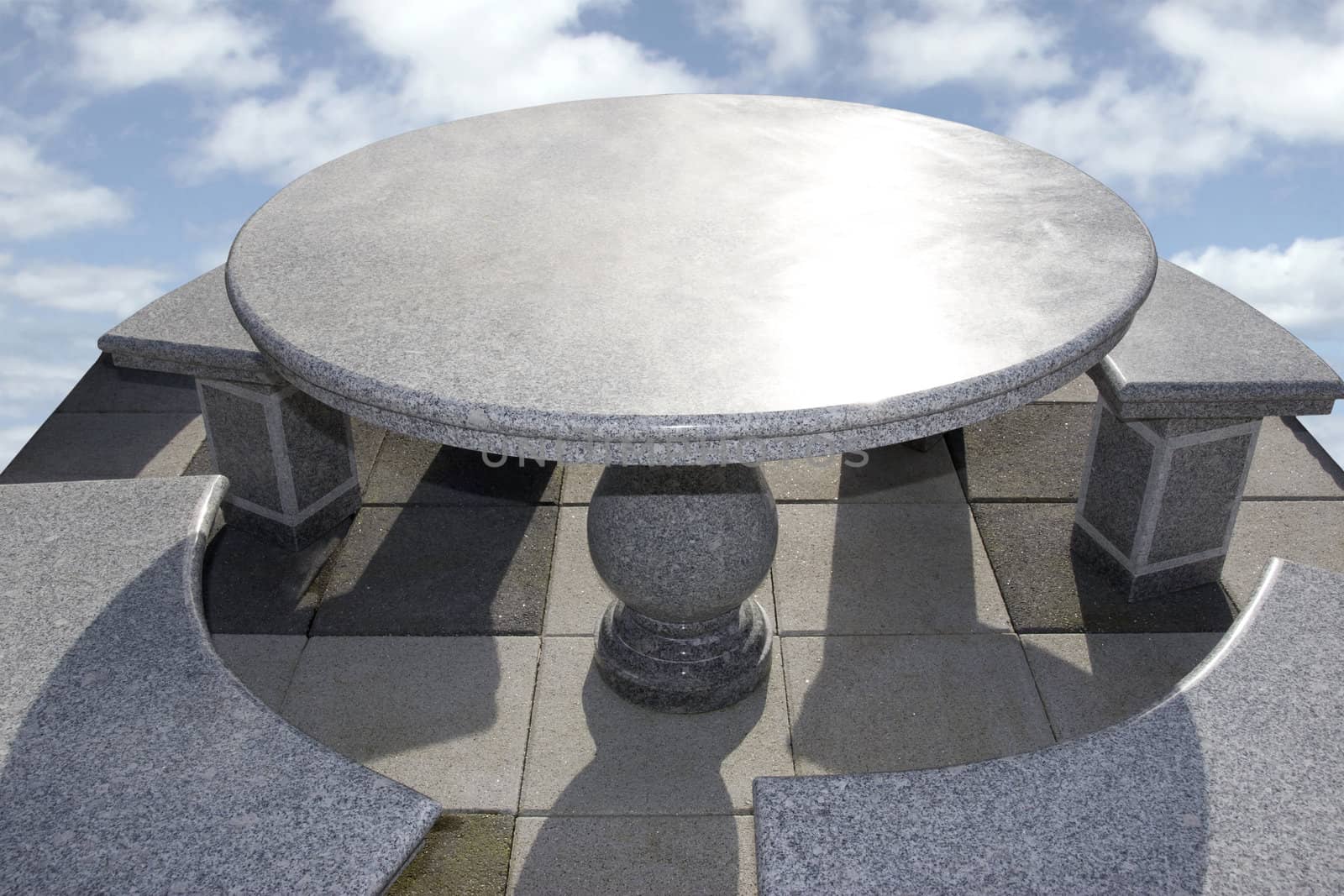 large marble table and chairs against a bright cloudy background