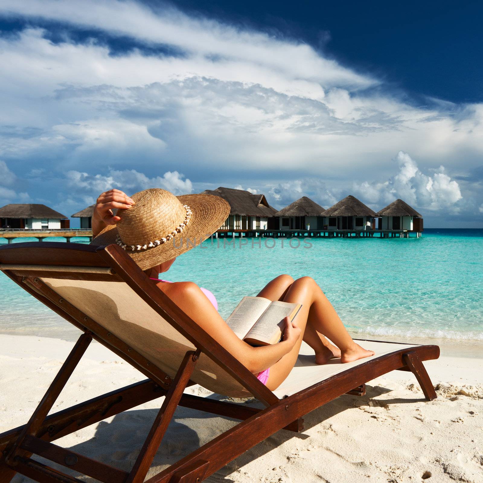 Young woman reading a book at beach by haveseen