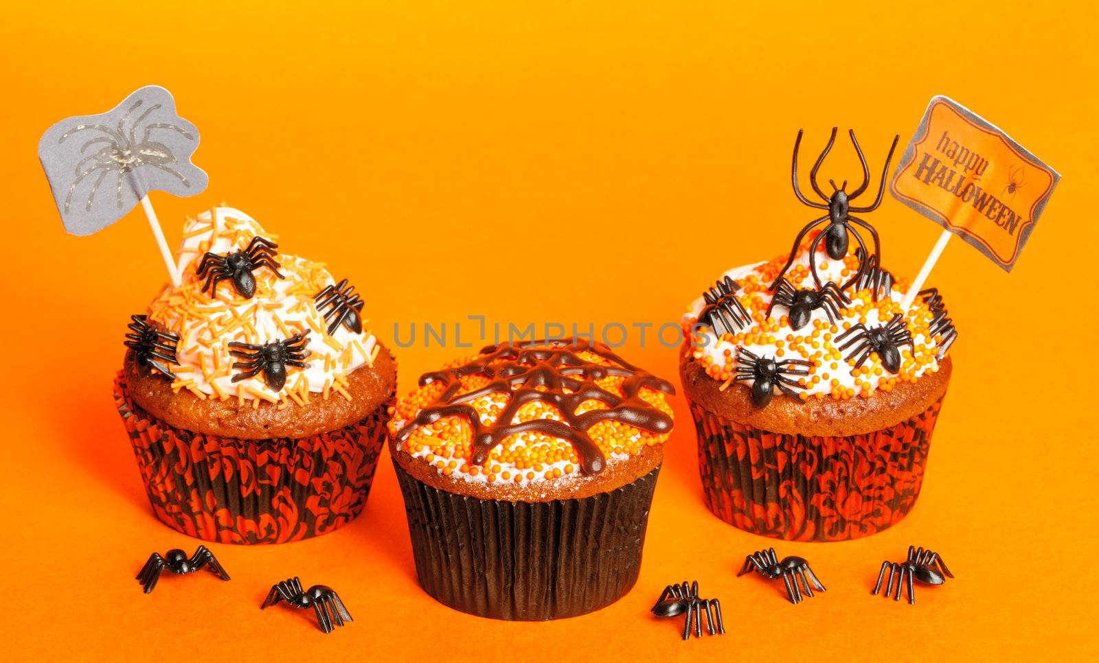 Halloween cupcakes with decoration over orange background
