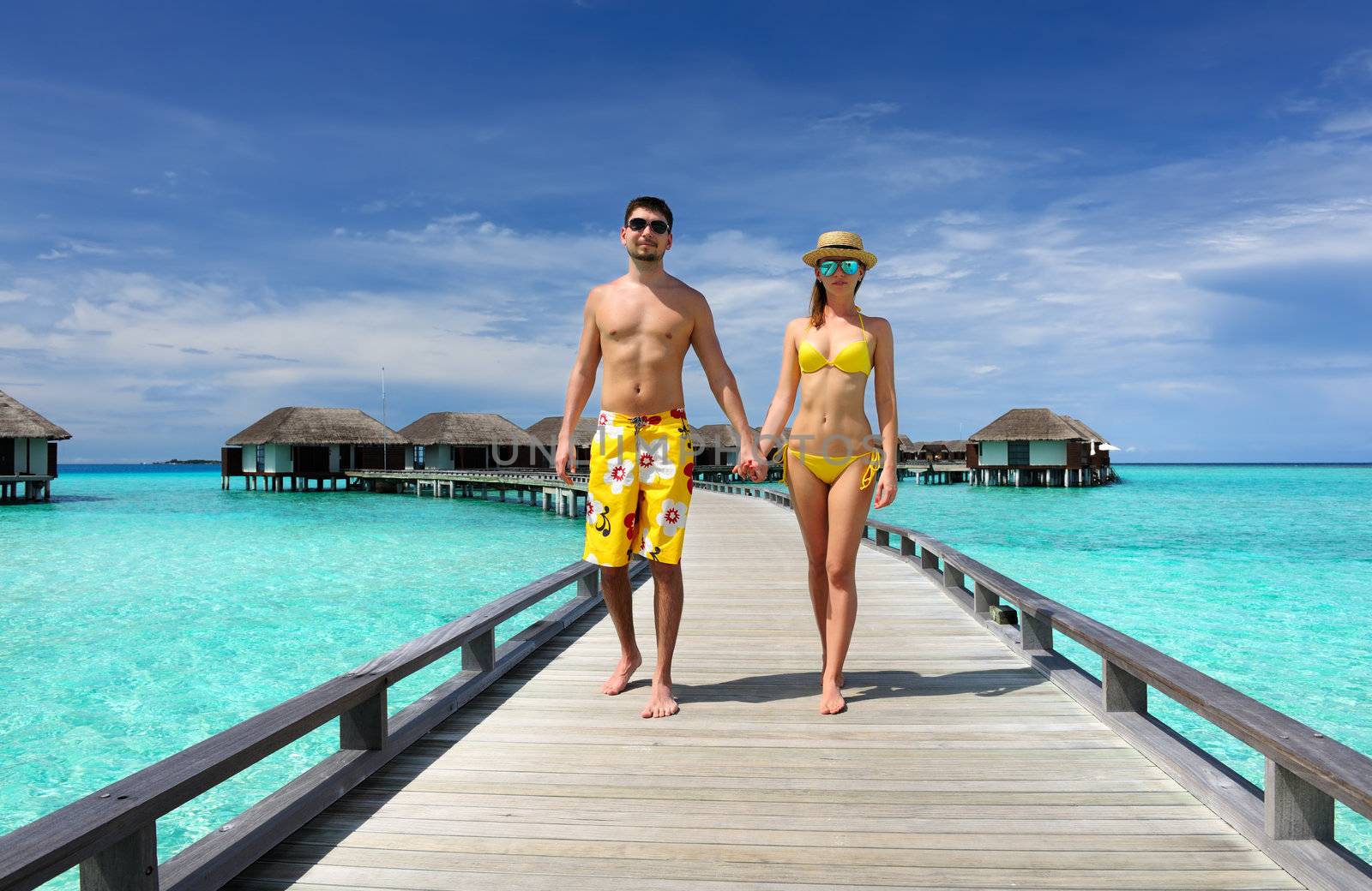 Couple on a tropical beach jetty at Maldives