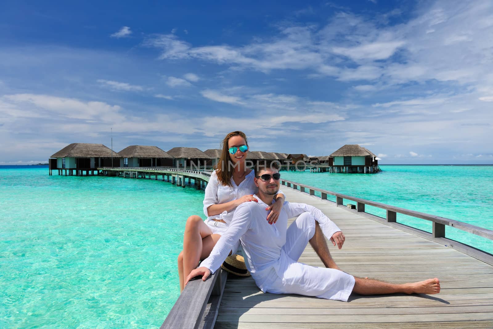 Couple on a tropical beach jetty at Maldives