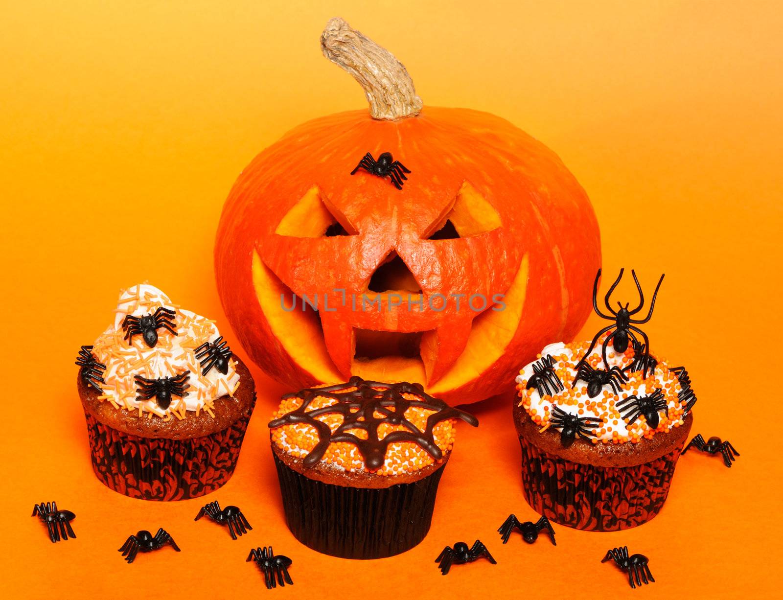 Halloween cupcakes with decoration over orange background
