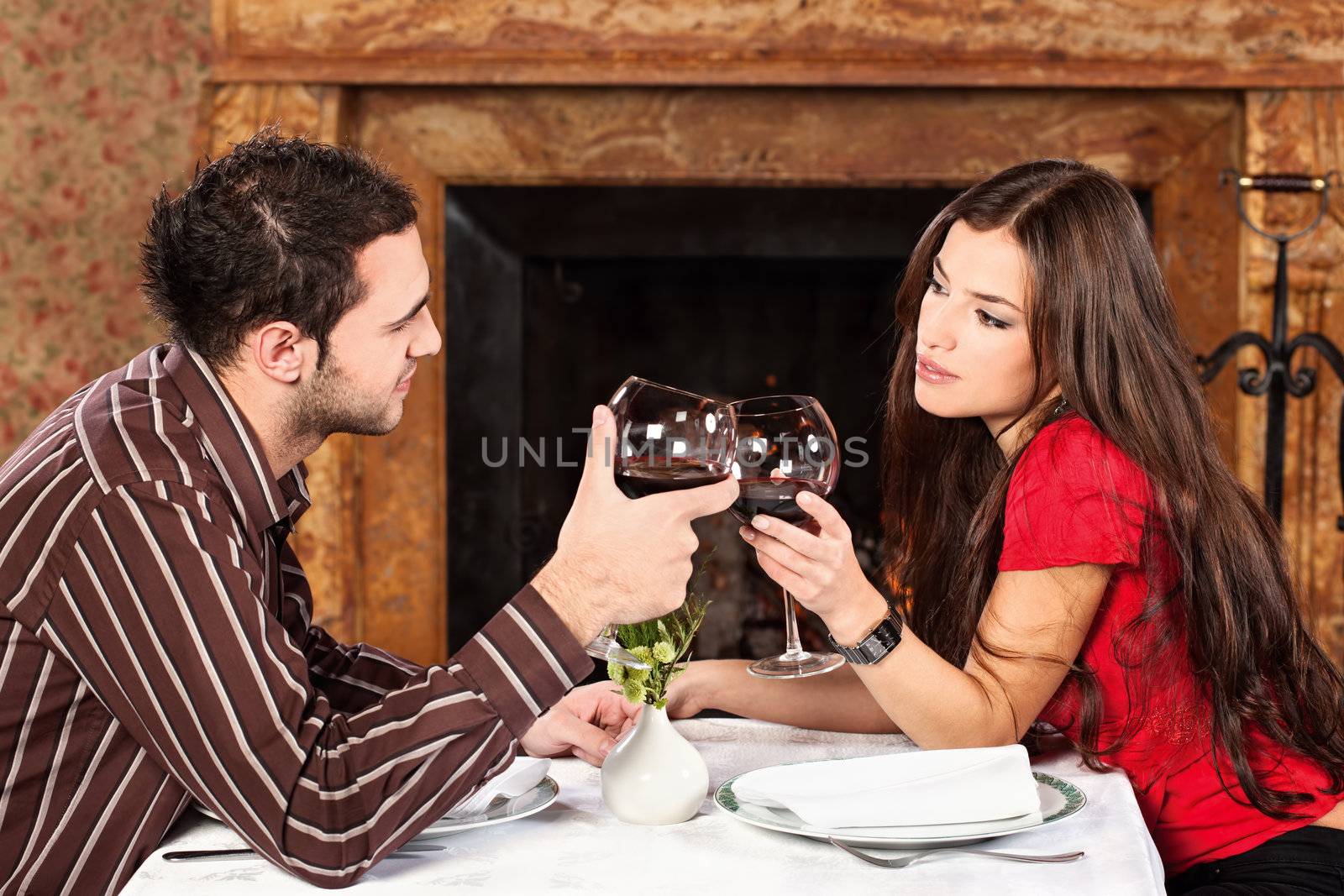 Young couple holding glasses of wine and cheers