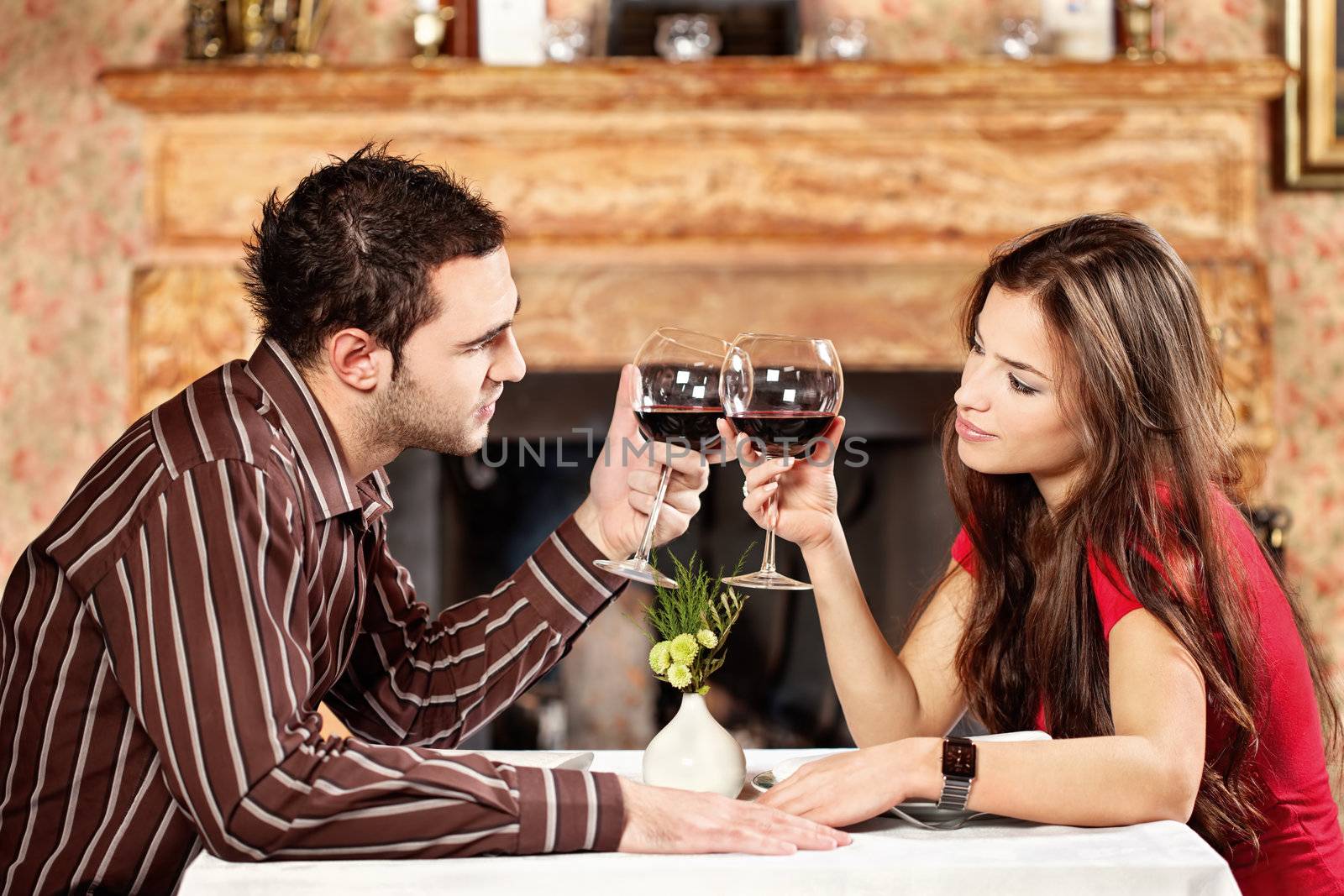 Young couple holding glasses of wine and cheers