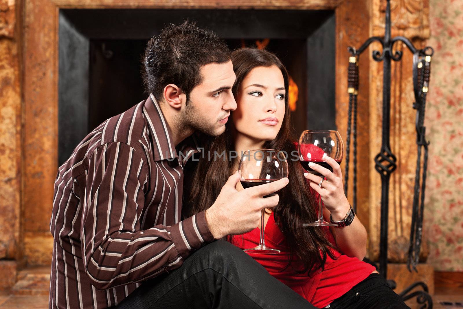 Couple in love enjoying wine near fireplace