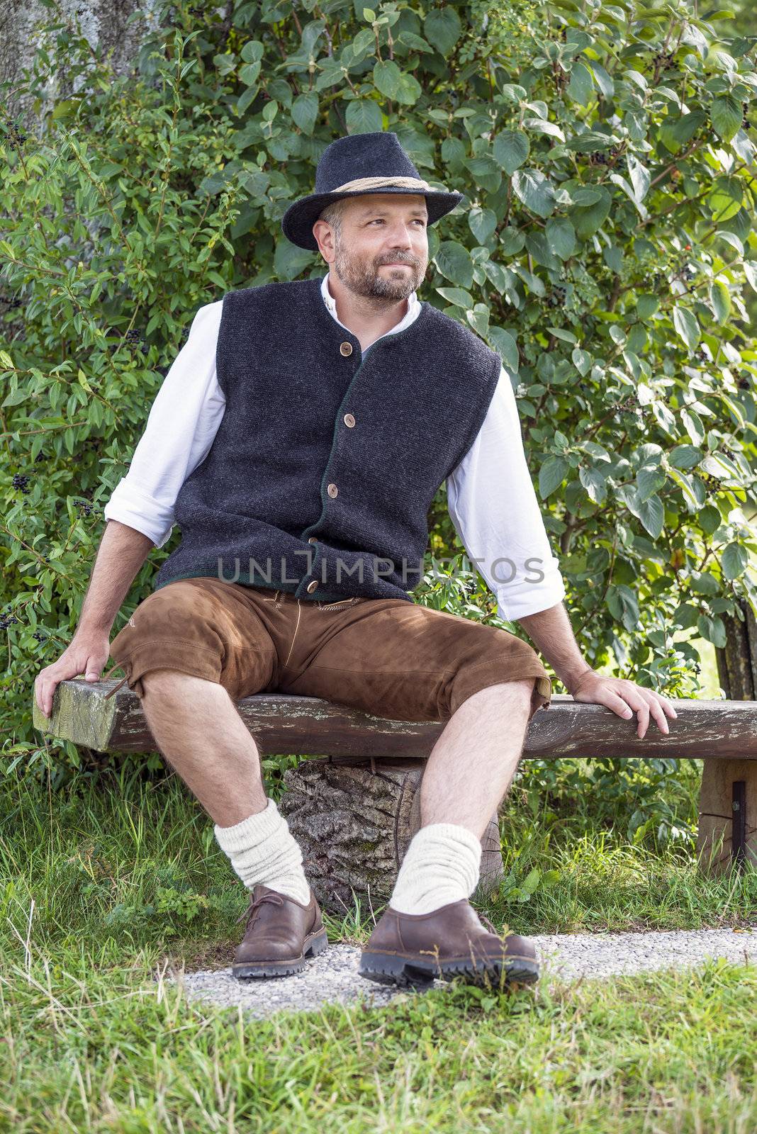Seated man in traditional Bavarian costumes and black hat by w20er