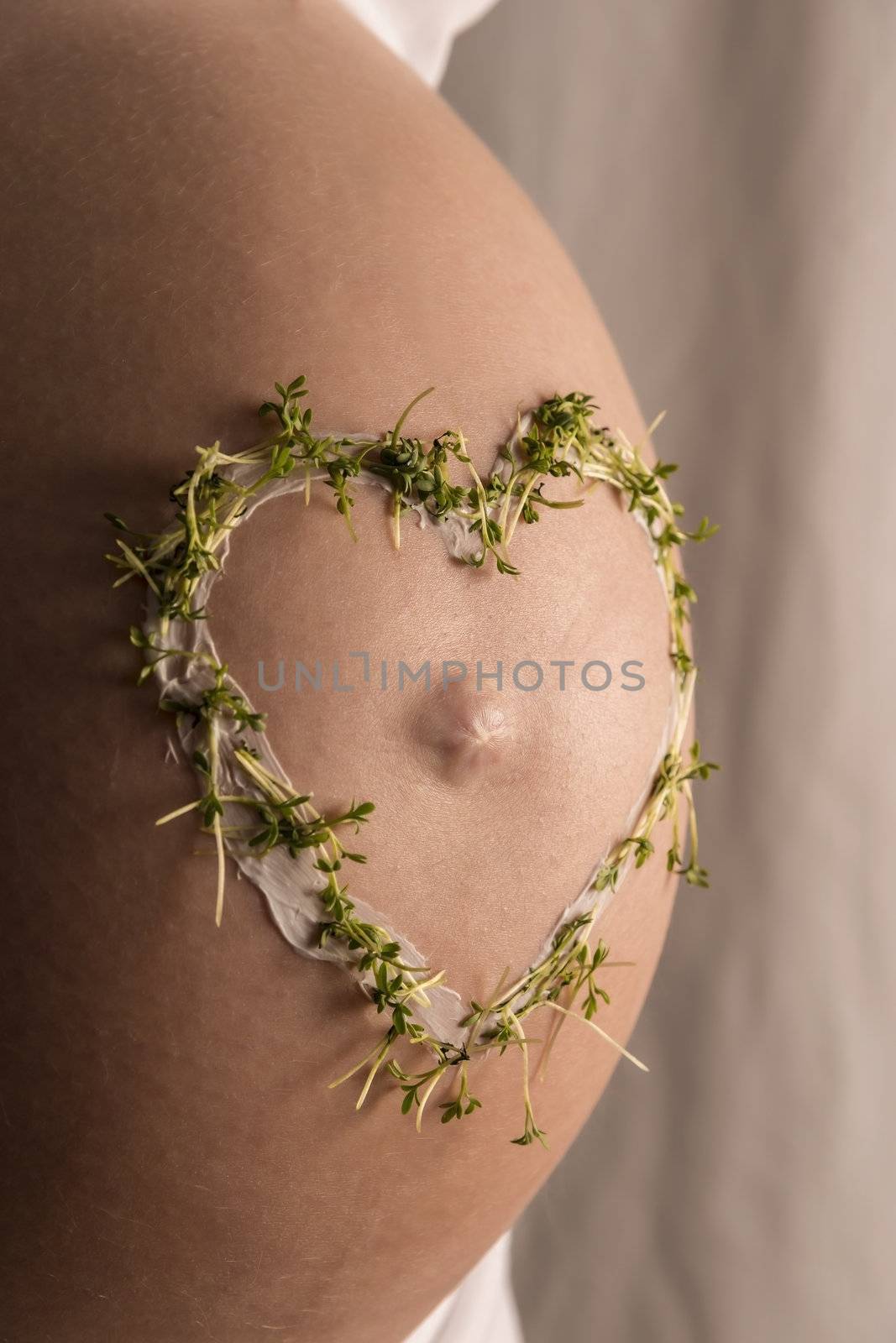 Close up of young woman wiht a cress heart on her baby bump