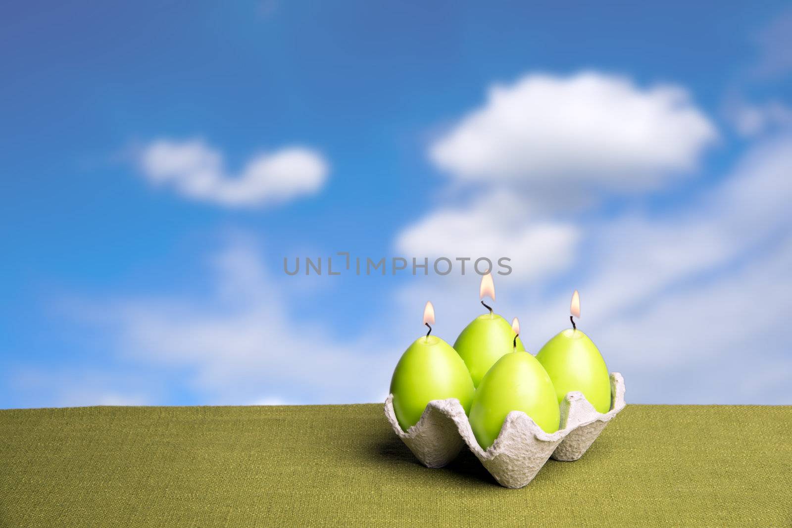 Green easter egg candels with blue sky and white clouds