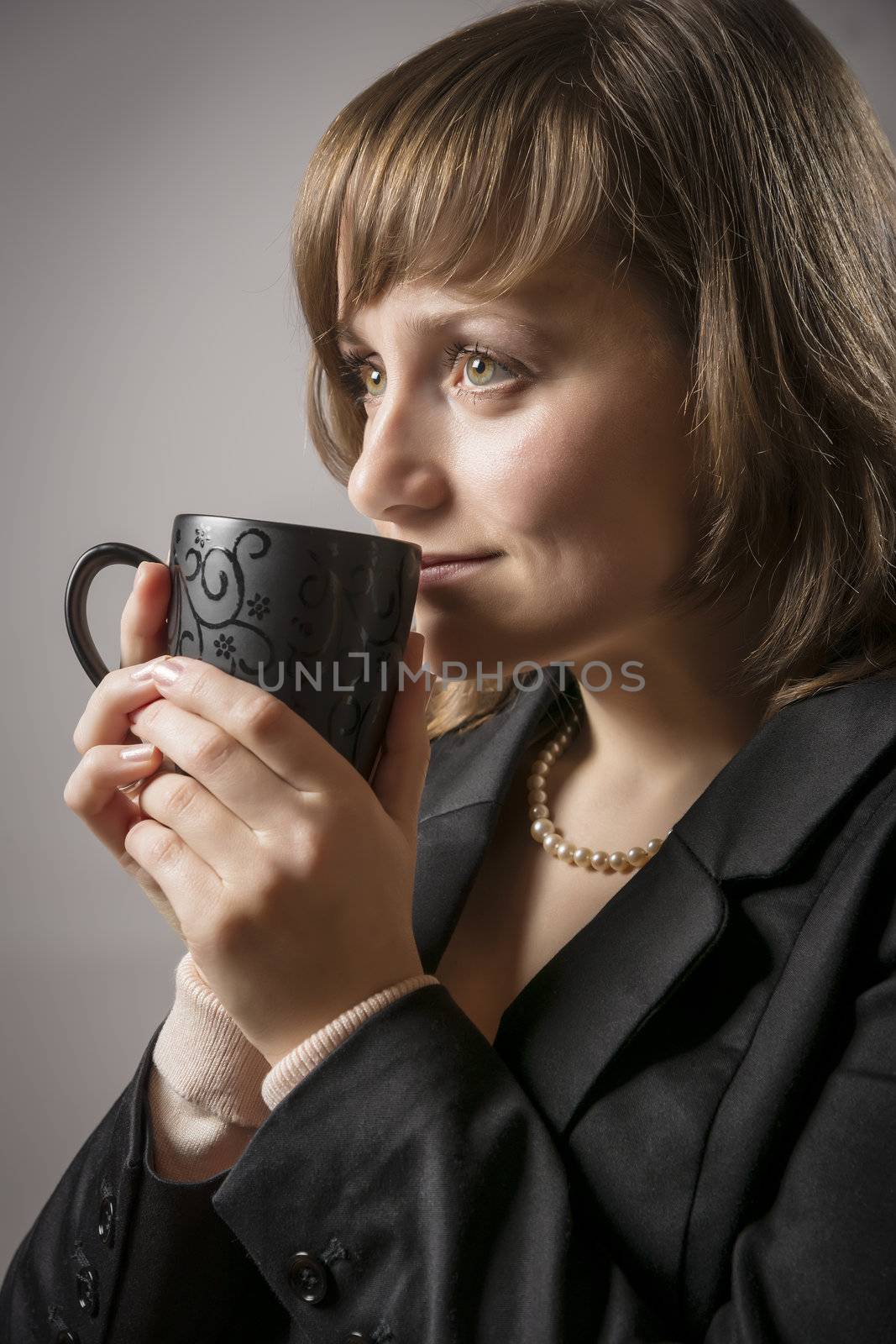 Young woman in black jacket drinking from a cup