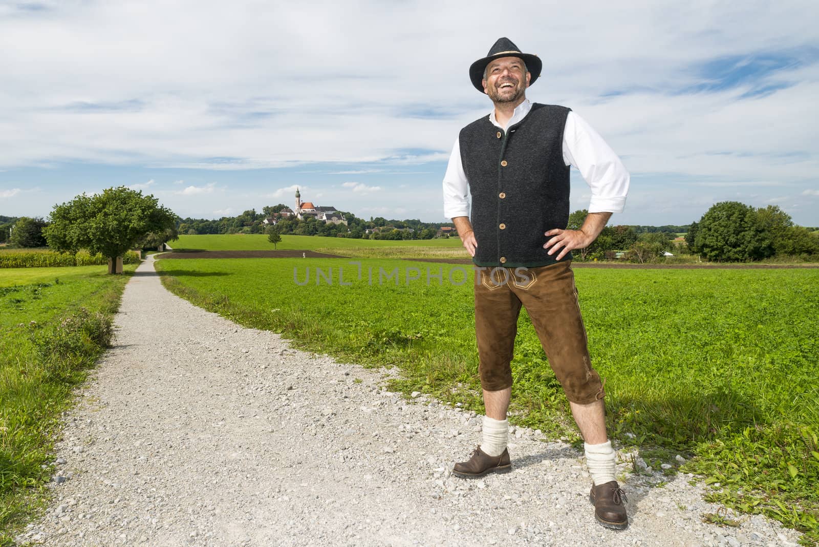 Man standing in Bavarian traditional costume on a sunny day in front of Andechs monastery