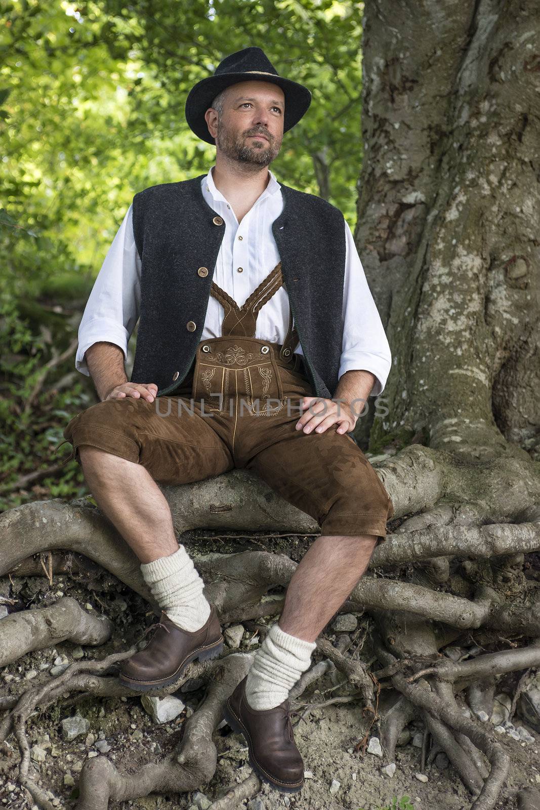 Seated man in traditional Bavarian costumes in forest
