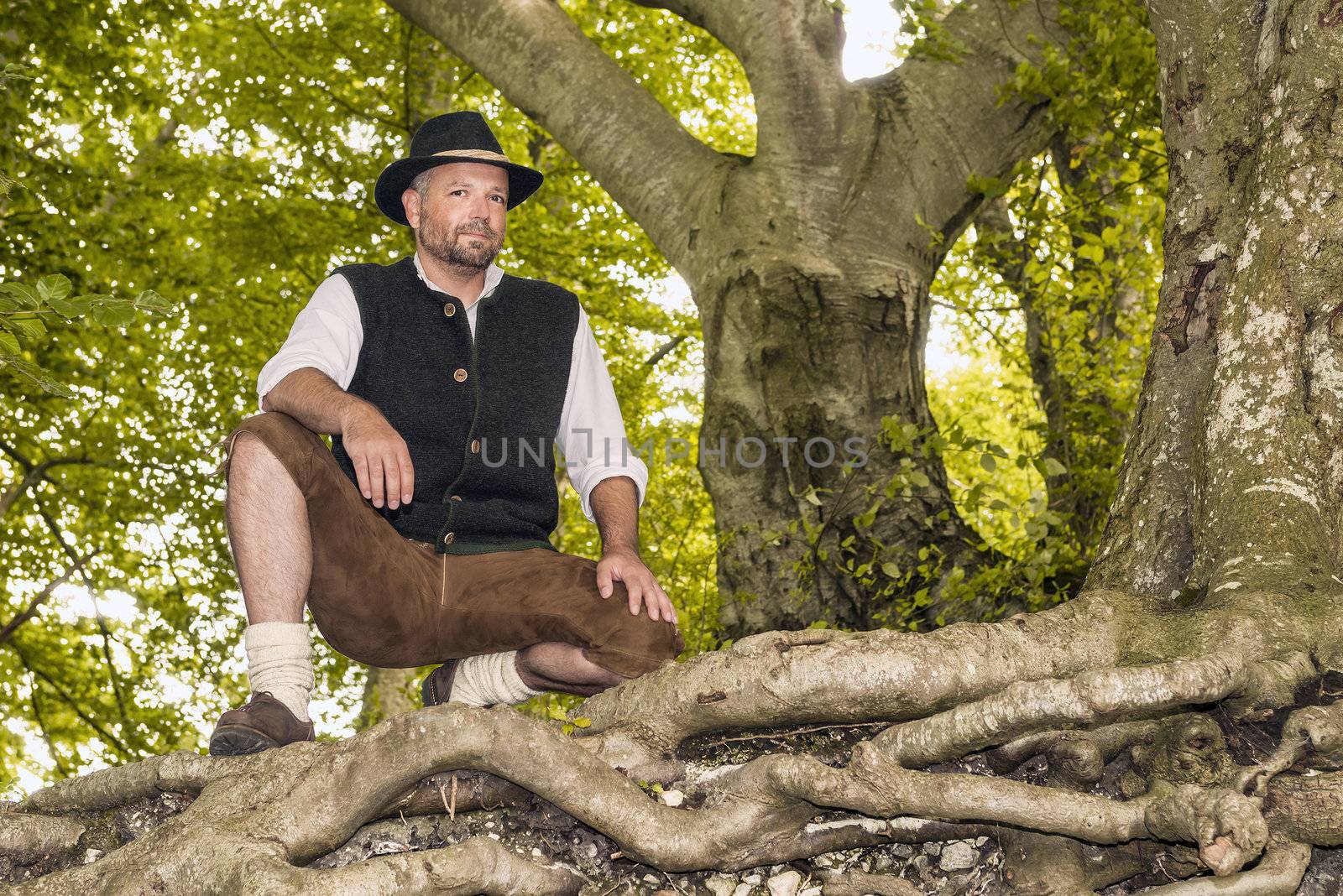 Kneeling man in traditional Bavarian costumes in forest
