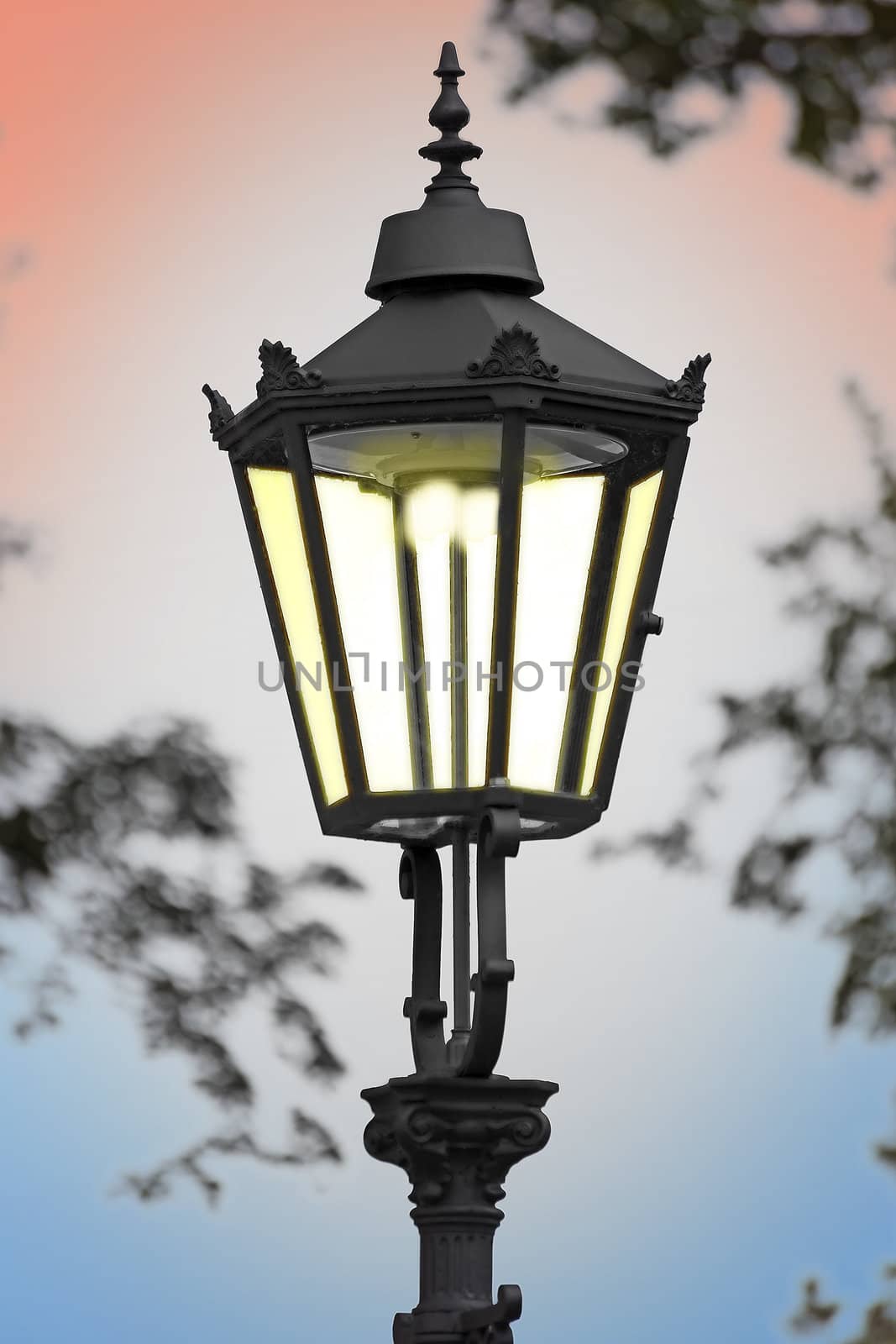 cast iron illuminated street lamp in the evening