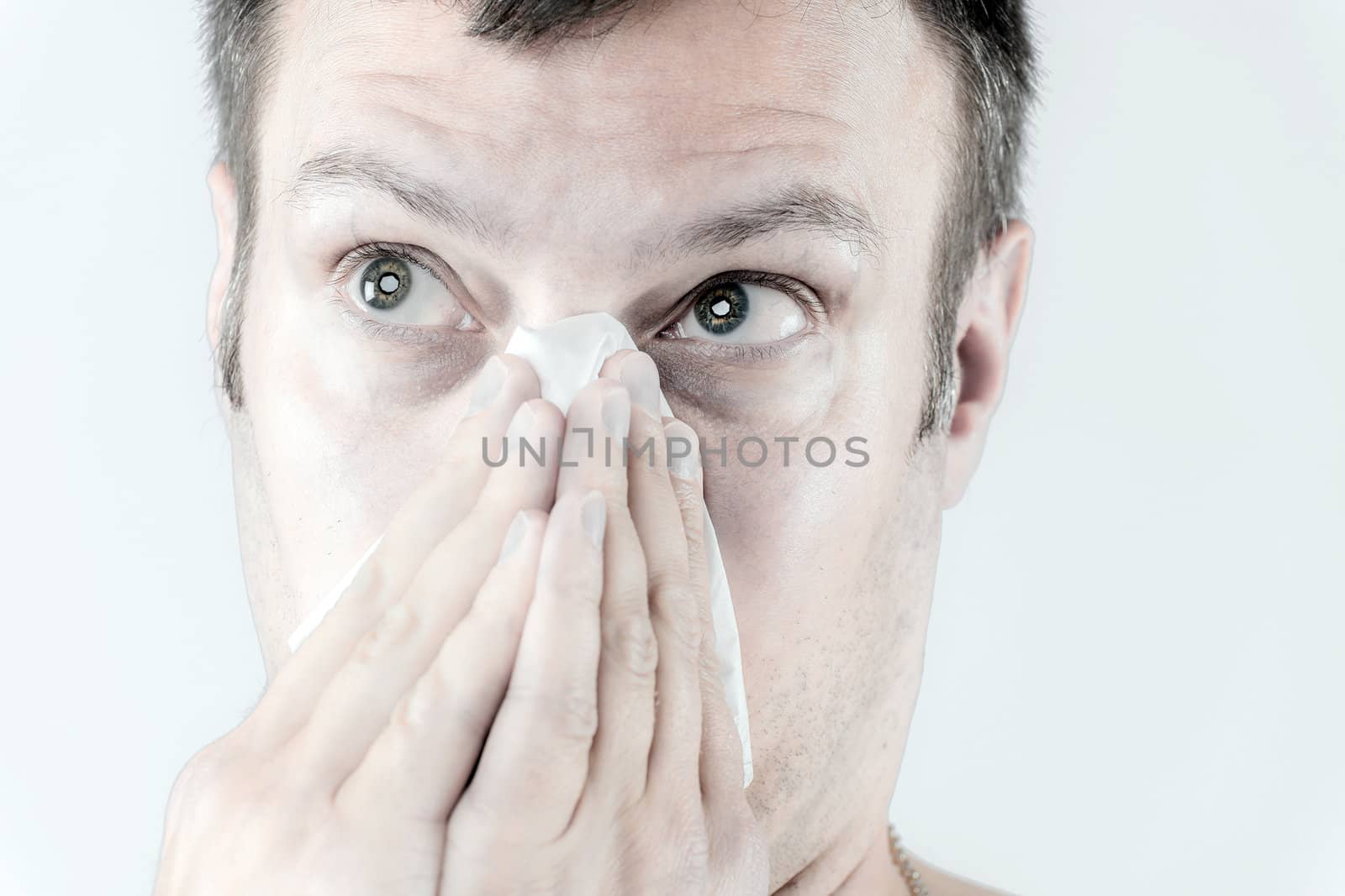 Portrait of a man who is sneezing in a tissue