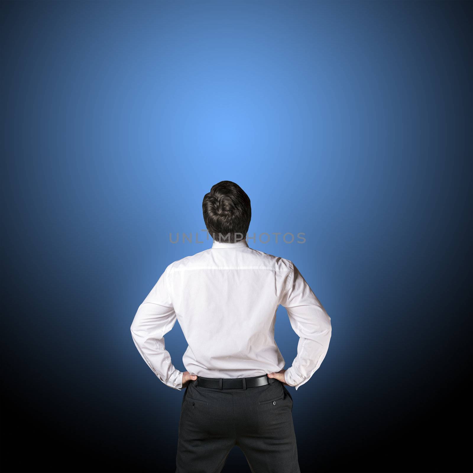 Backside of a business man in black business trousers and white business shirt with a blue-black background