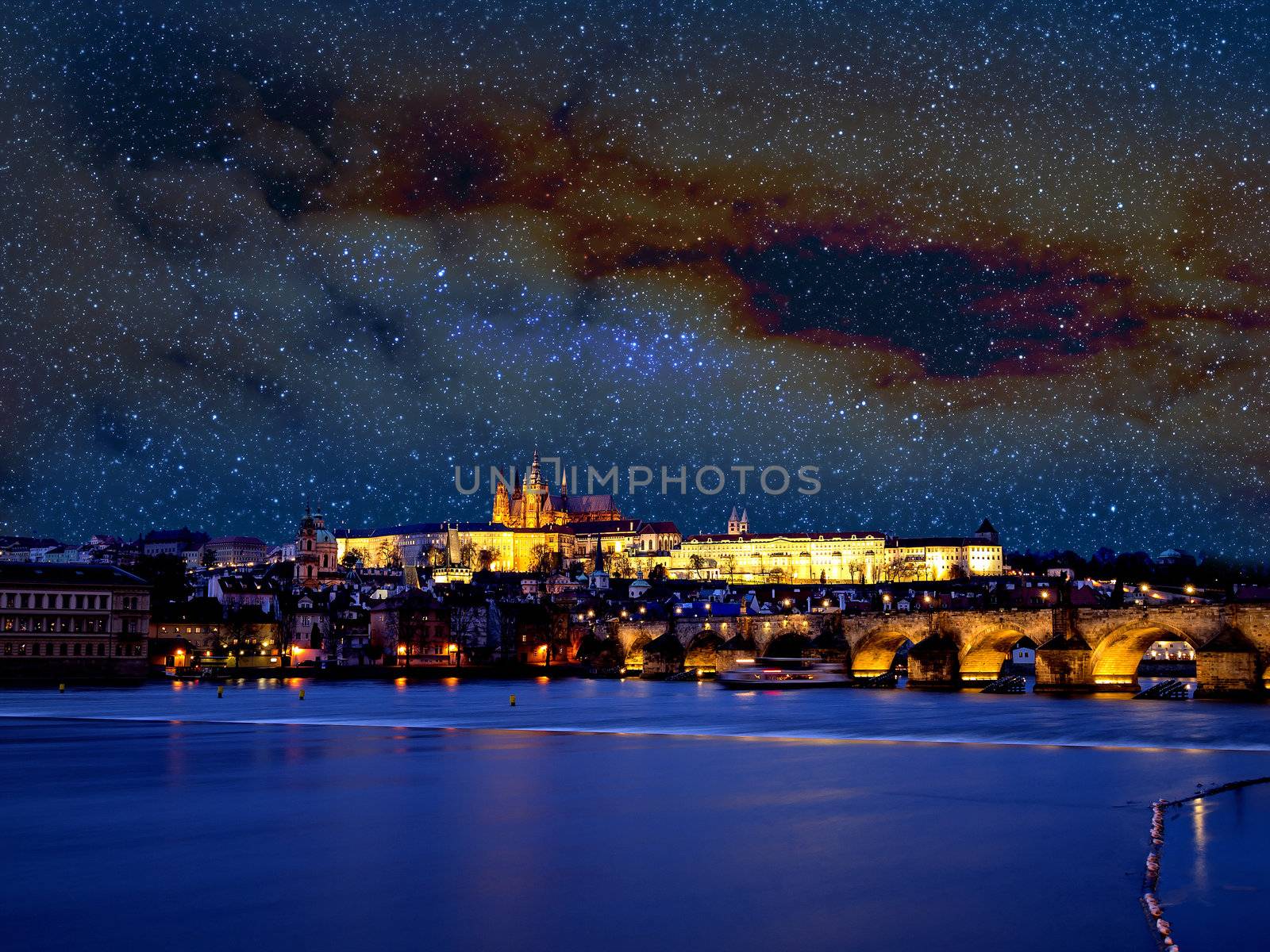 View to illuminated Prague with Charles Bridge, Hradcany Castle and Vitus and stars in the sky in the evening at January 