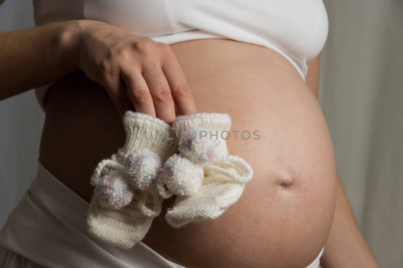 Young woman holding baby shoes in front of her baby bump