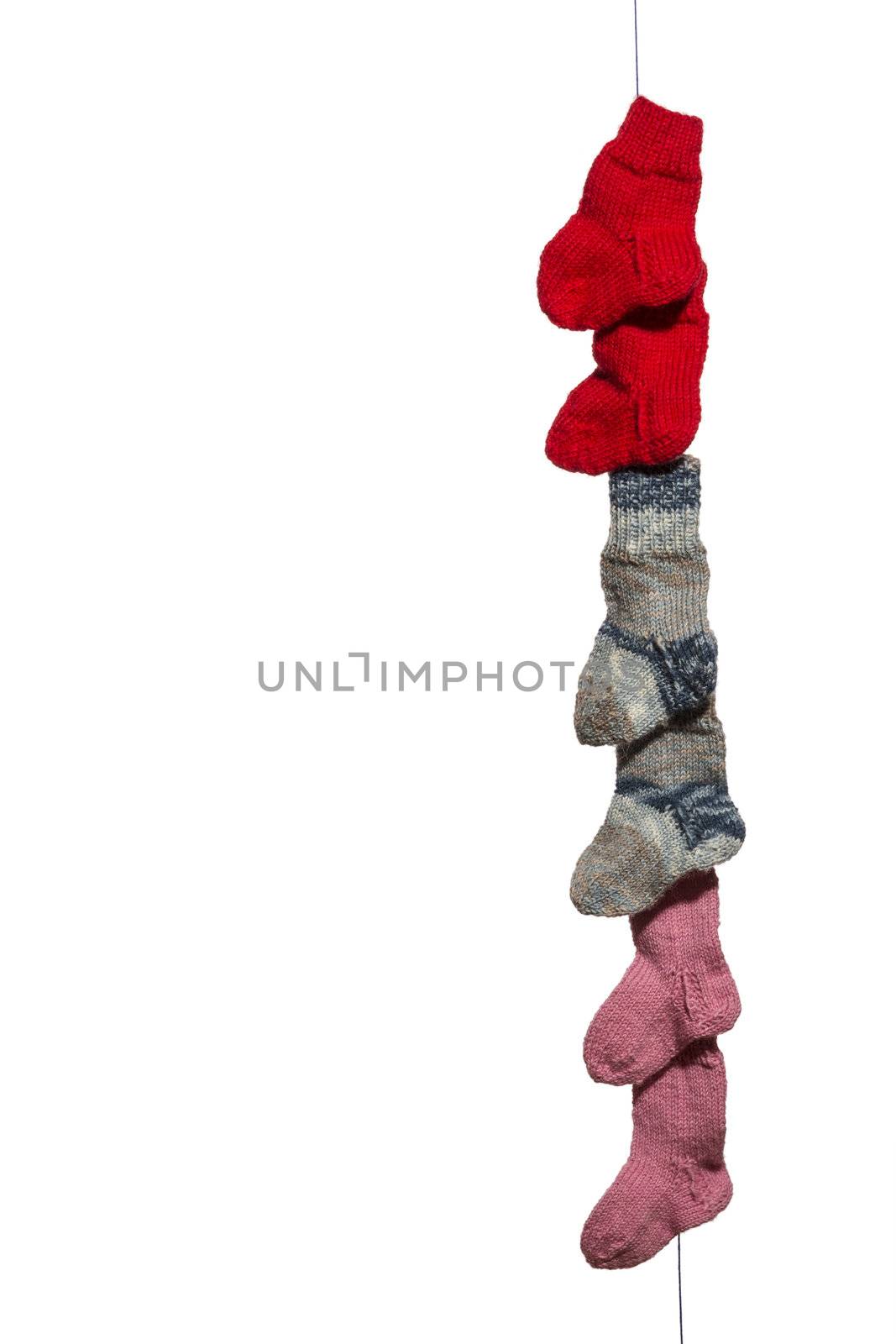 Blue, red, pink and white babysocks on a line in front of a white background