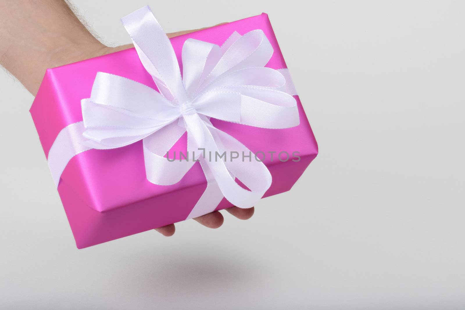 gift with white ribbon in purple paper on white underground
