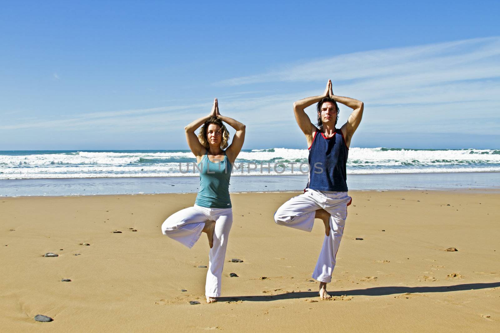 Couple doing yoga excersises at the beach by devy