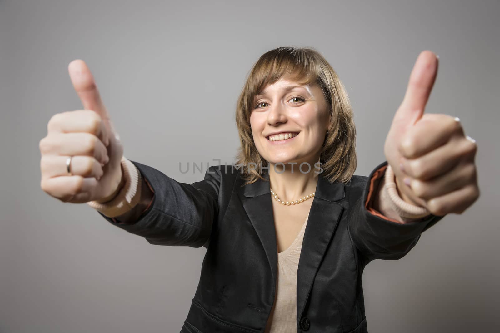 Young brunette business woman with black clothes is holding high two thumbs