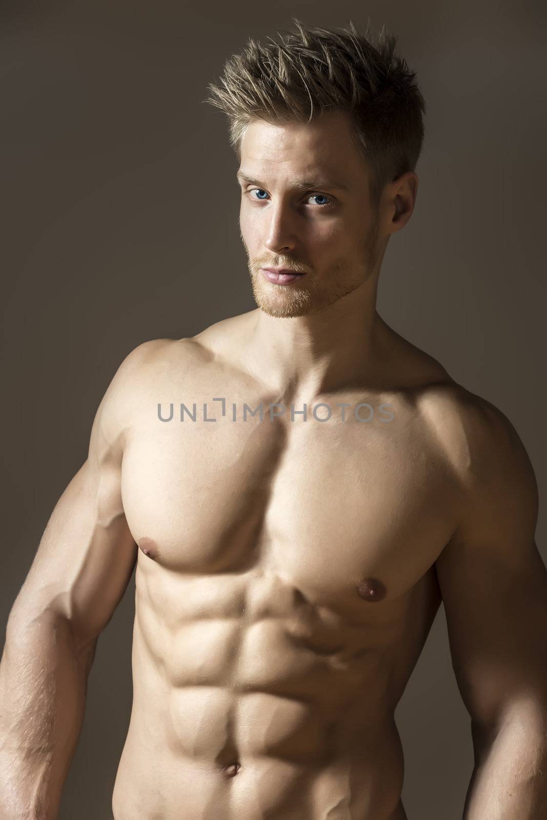 Blond athletic man with well developed abs and pecs look to you