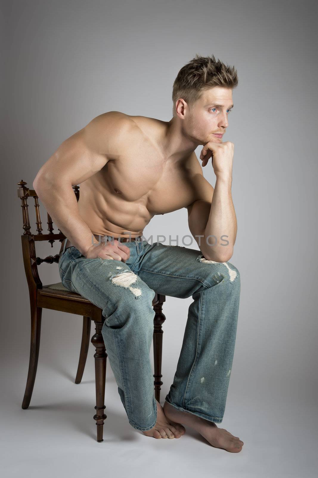 Thinking athlete with well trained muscles sit on a chair