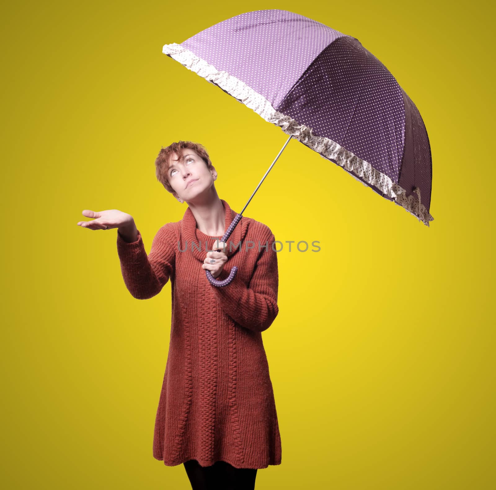 beautiful woman with sweater and umbrella on yellow background
