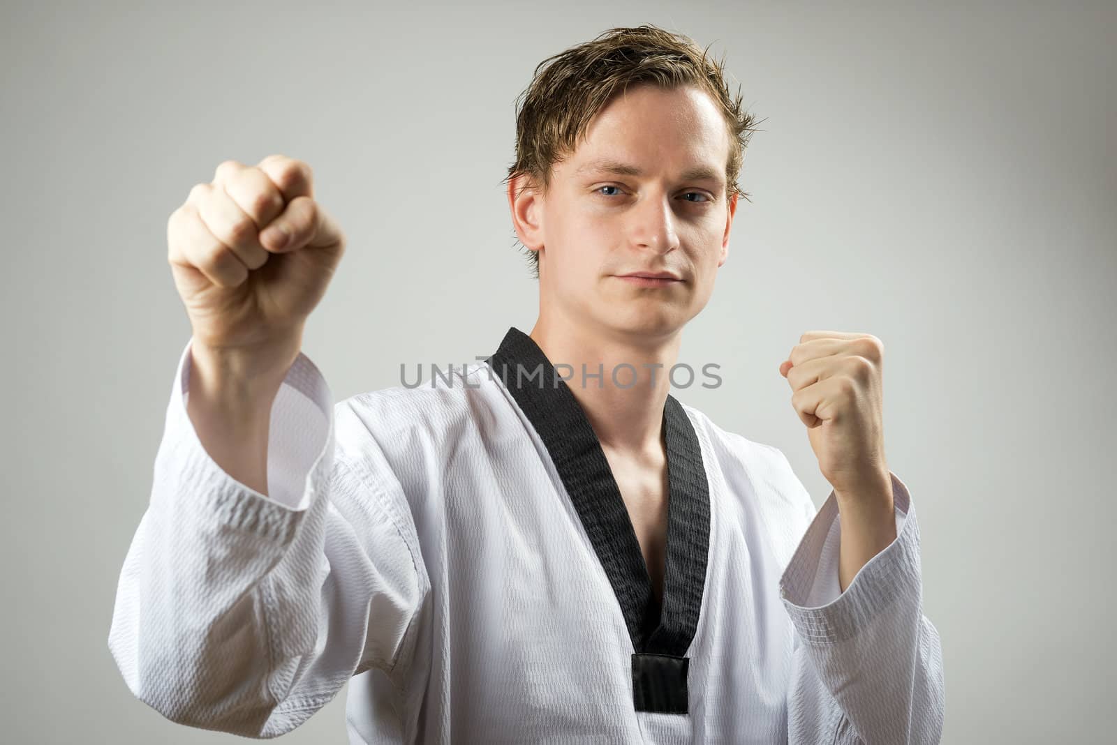 Taekwon-Do champoin on a grey background and doing a double block