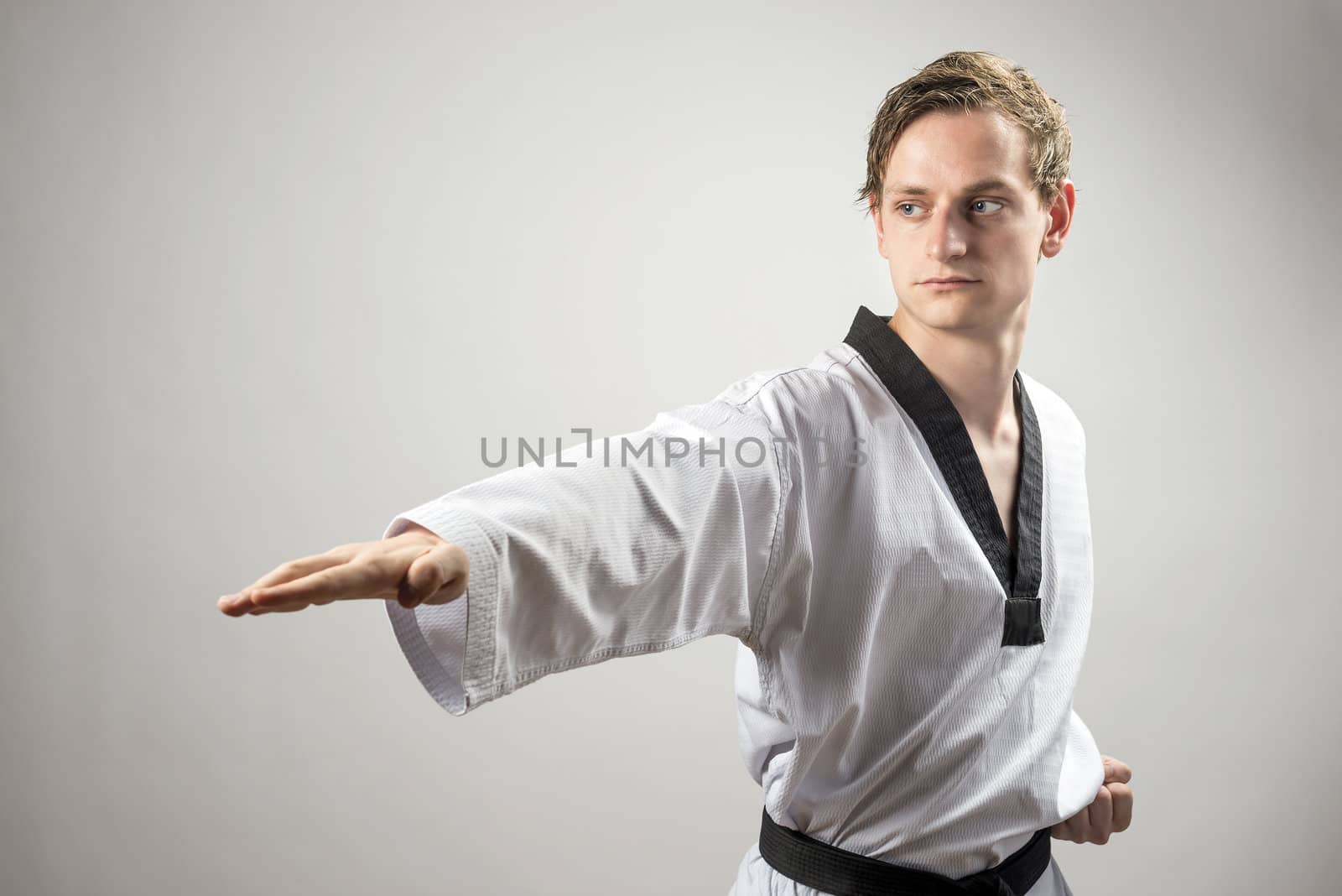 Taekwon-Do champoin on a grey background is showing hand technique