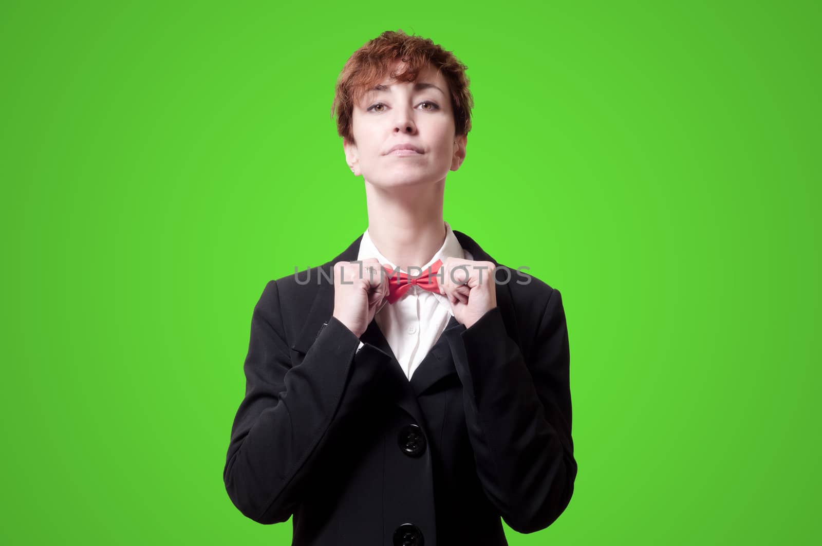 elegant businesswoman adjusting bow tie on green background