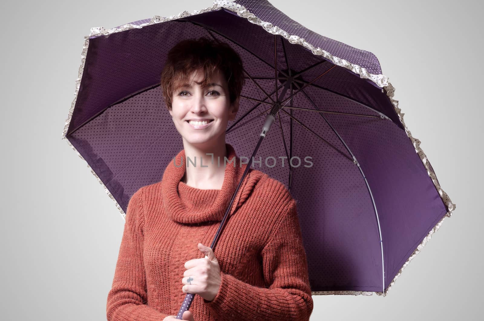 beautiful woman with sweater and umbrella on gray background