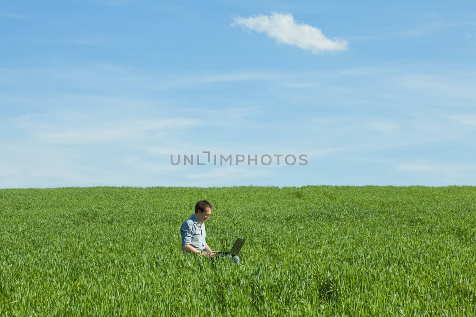 young man using laptop in the field