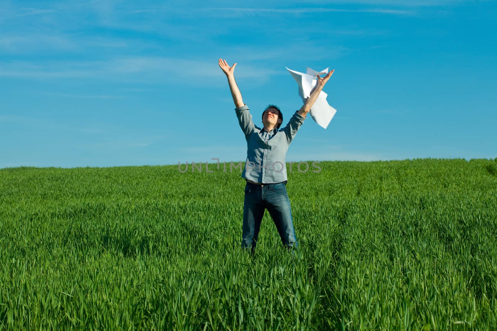 young man throwing a paper in the green field