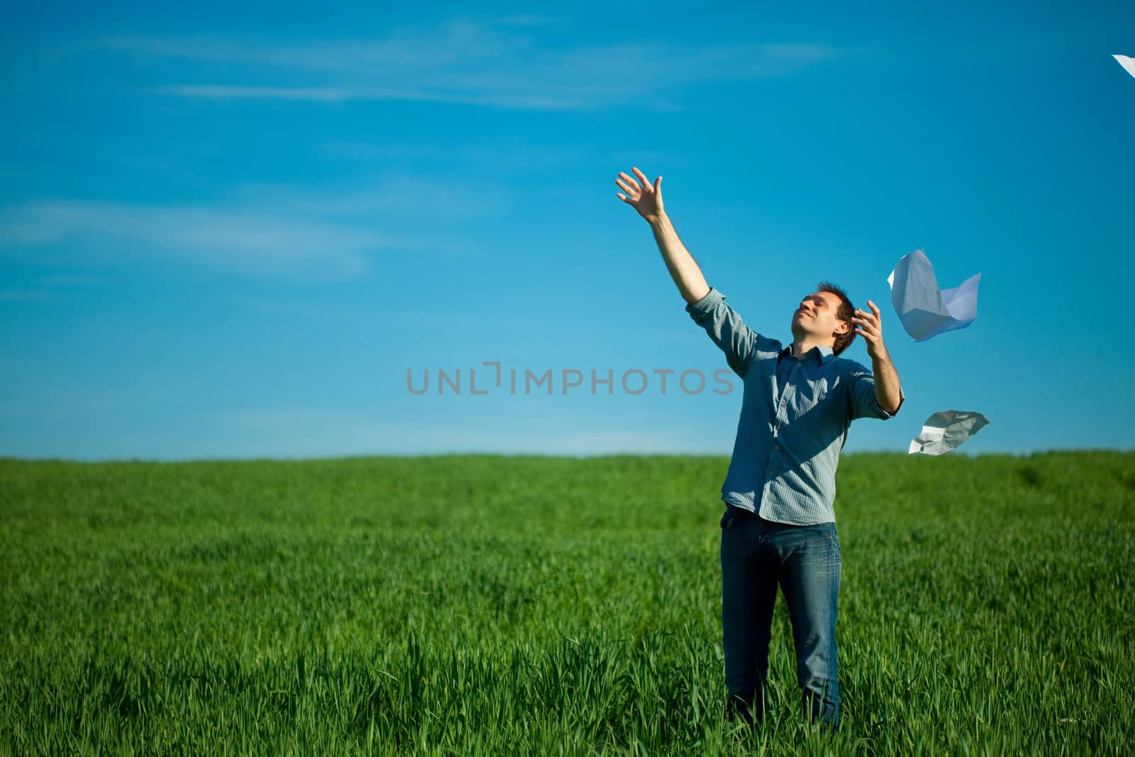 young man throwing a paper in the green field