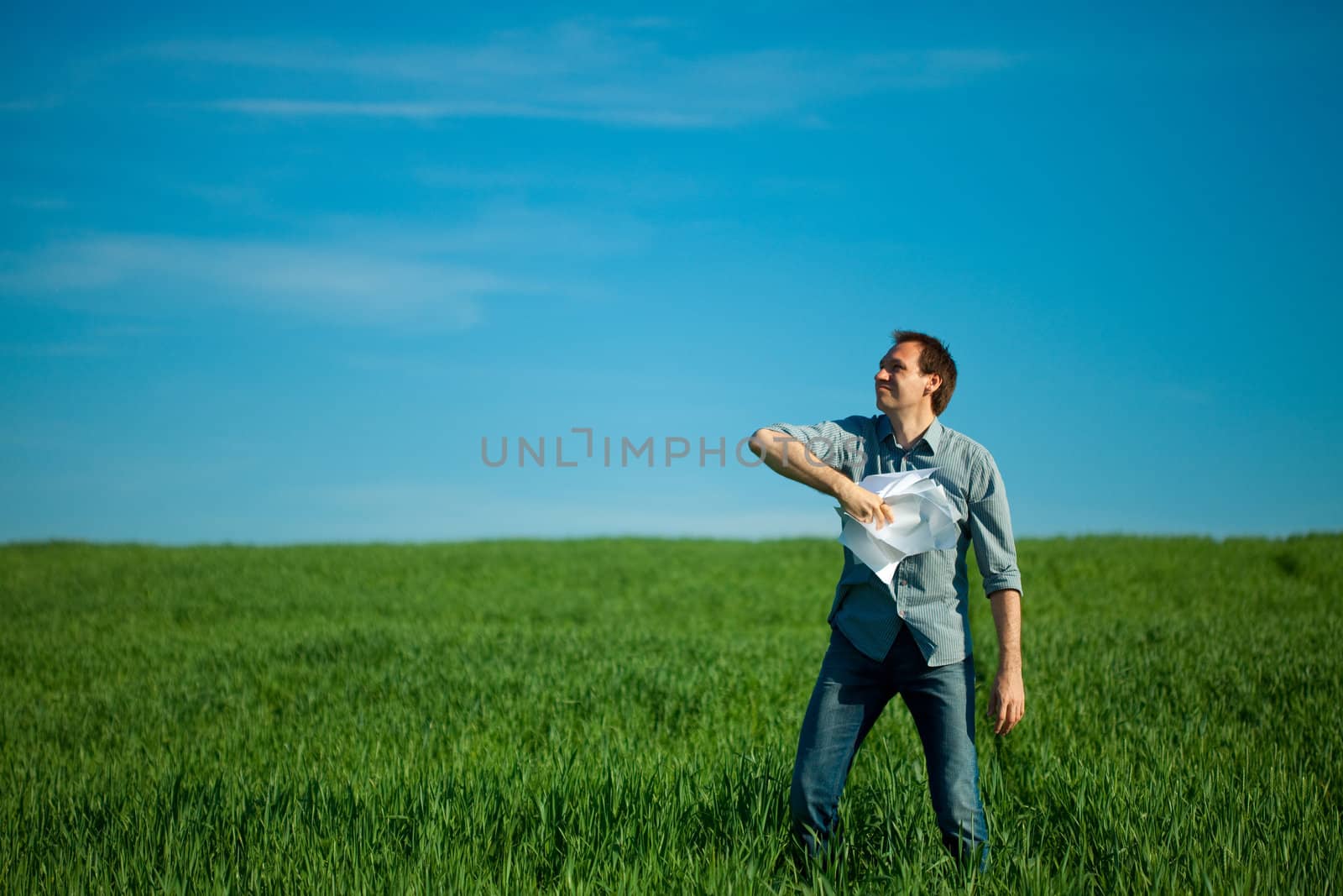 young man throwing a paper in the green field