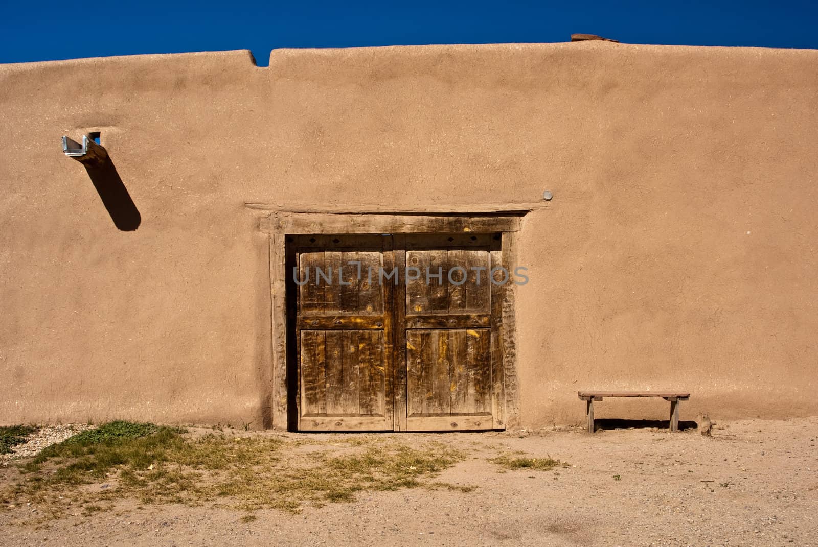 Adobe building with old door and bench by emattil