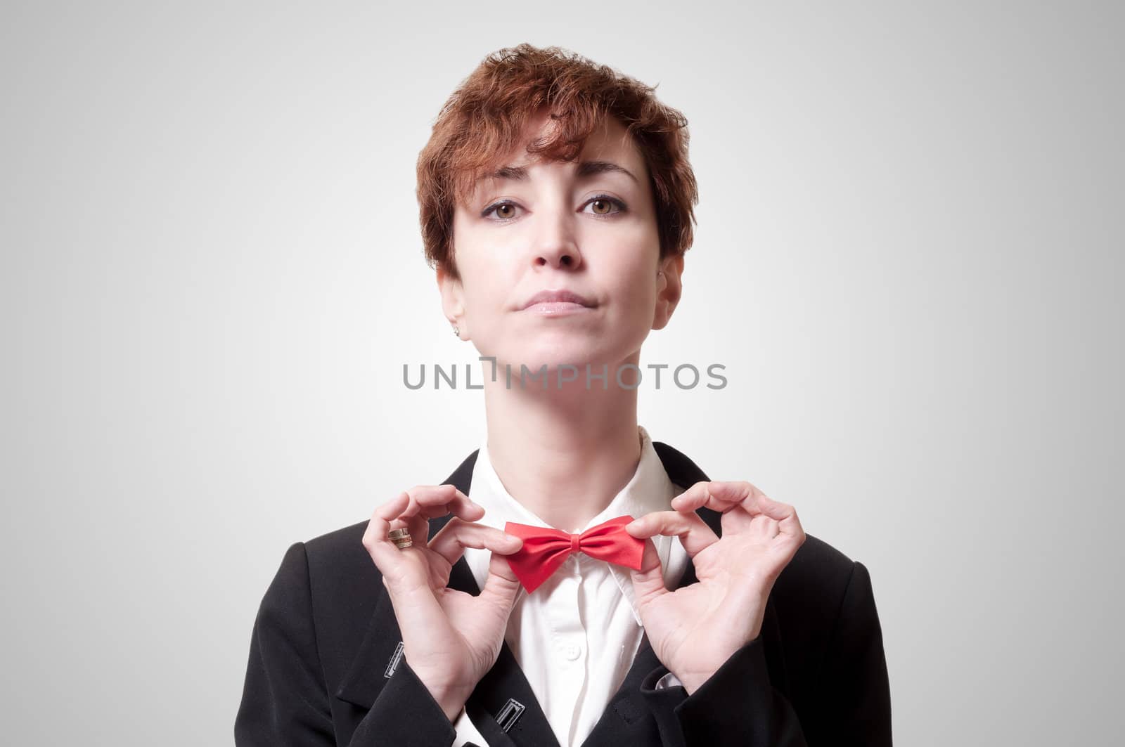 elegant businesswoman adjusting bow tie on gray background