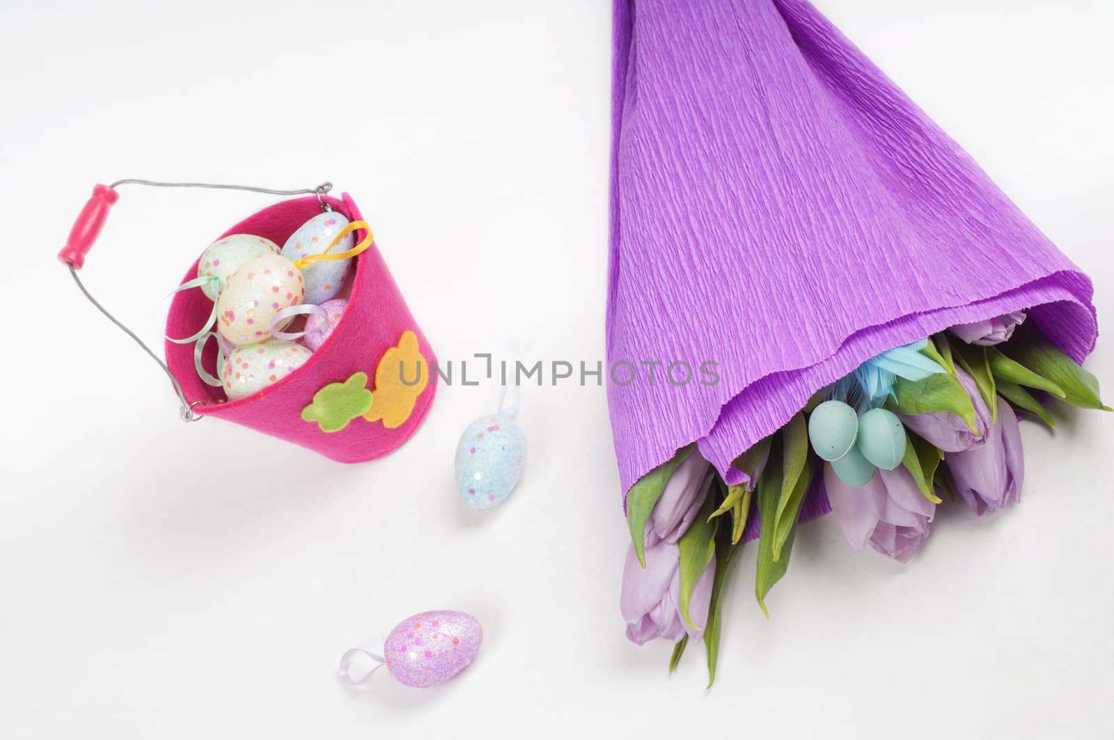 Easter eggs with tulips and bucket on light background