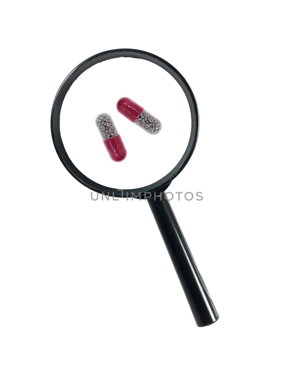 A magnifying glass magnnifying pills on a white background