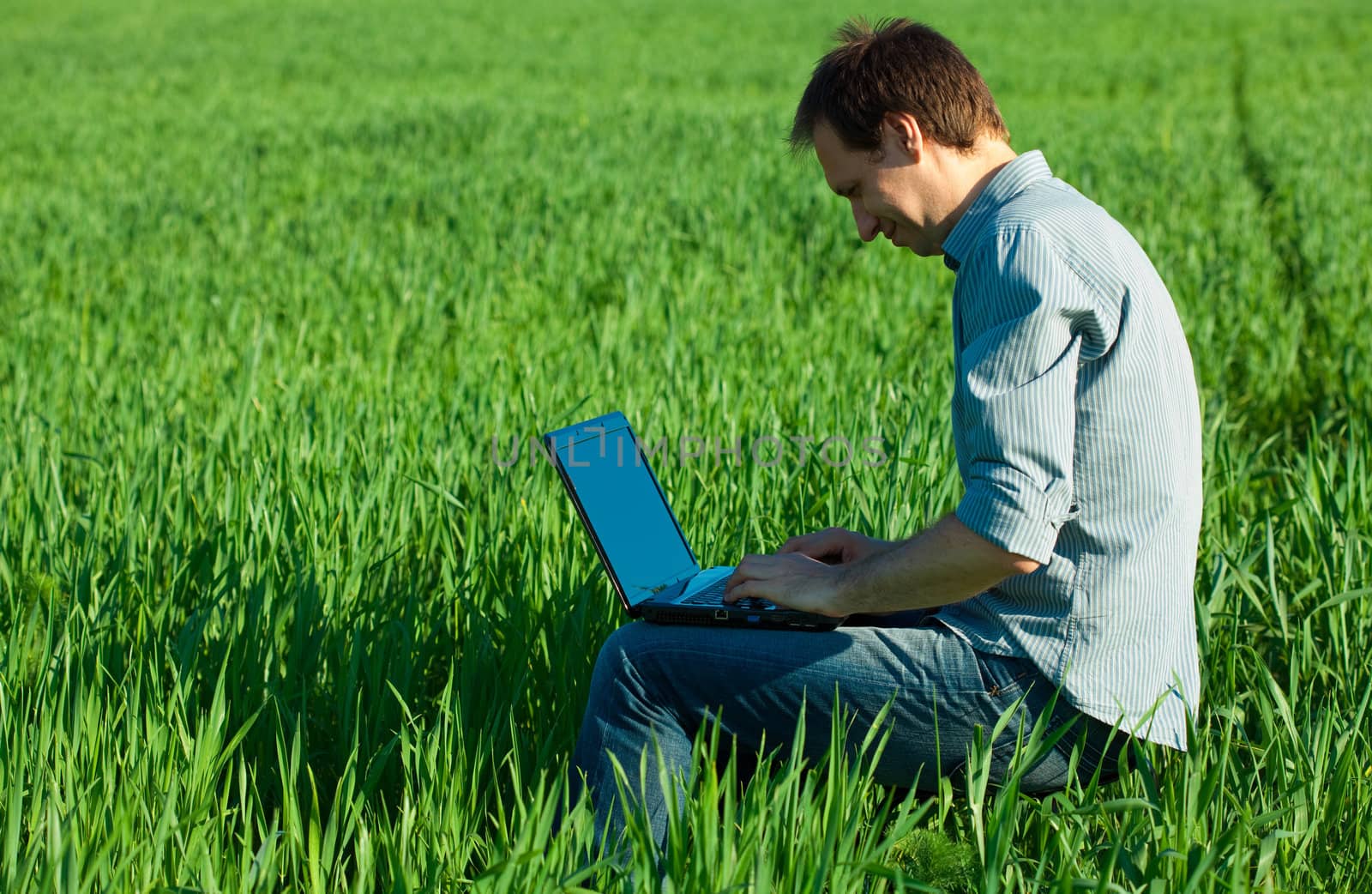 young man using laptop in the field