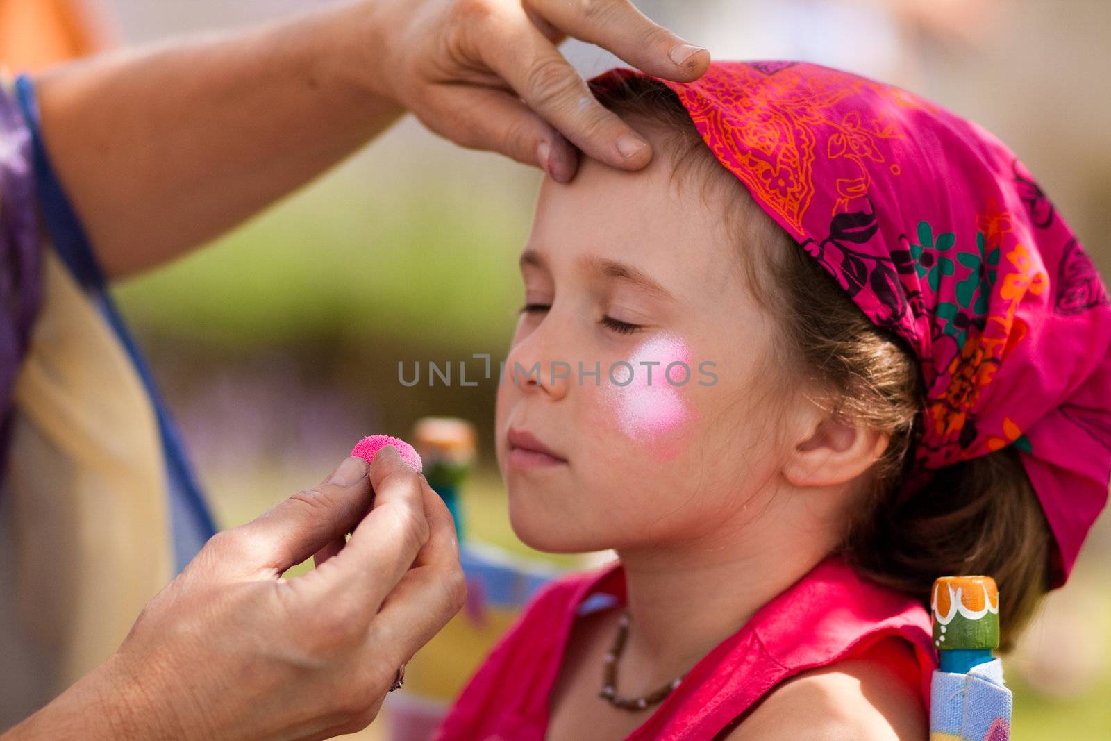 Cute little girl getting make-up on her face