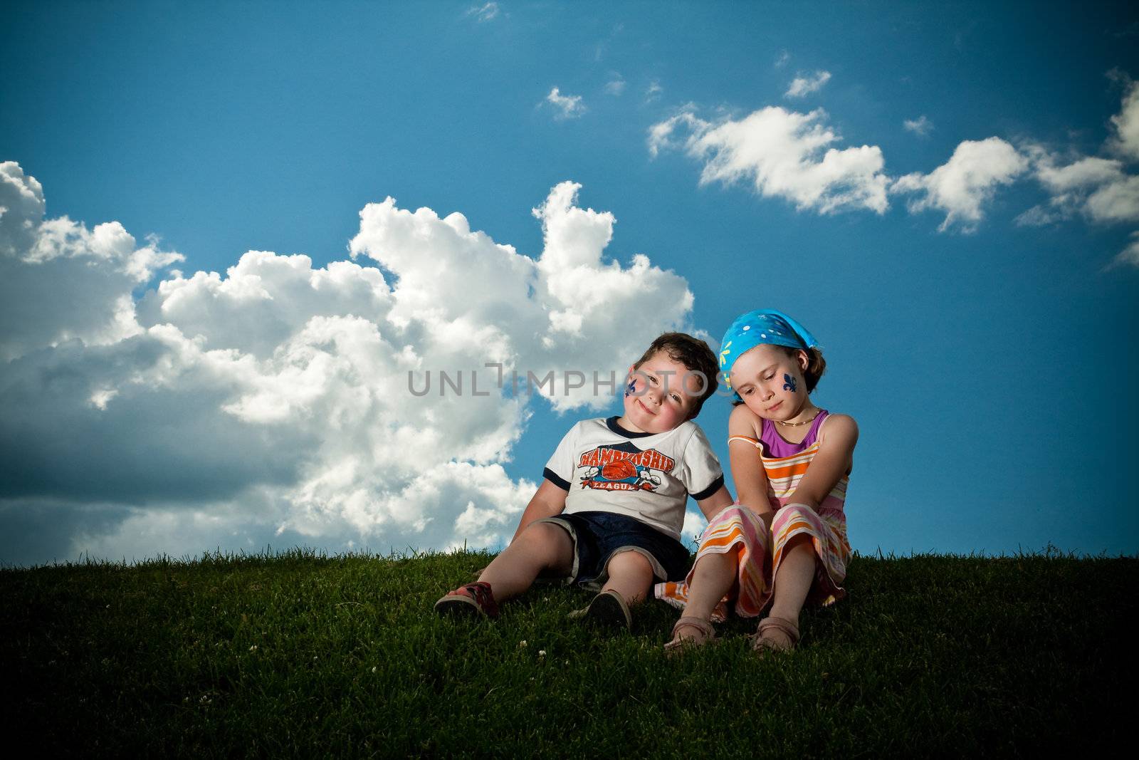Cute little girl and boy sitting on the grass on the grass
