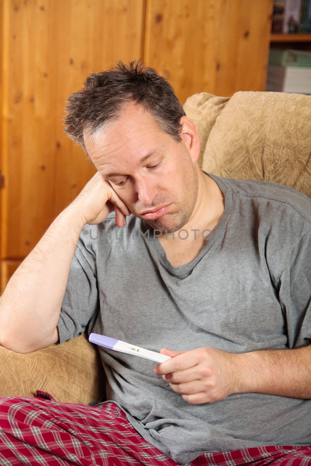 Sad man looking at a positive pregnancy test