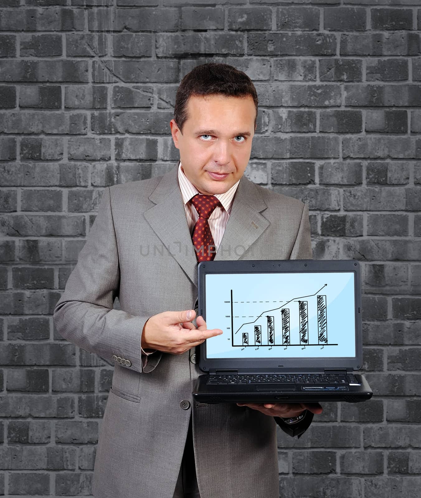 businessman with a laptop in hand points to chart of profits
