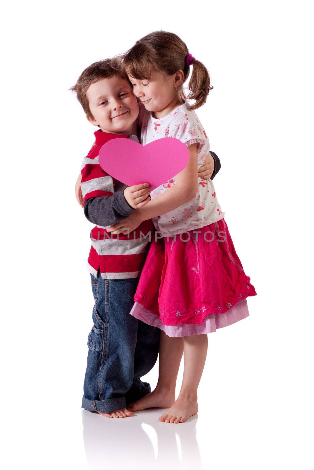 Cute little children hugging and holding a pink heart