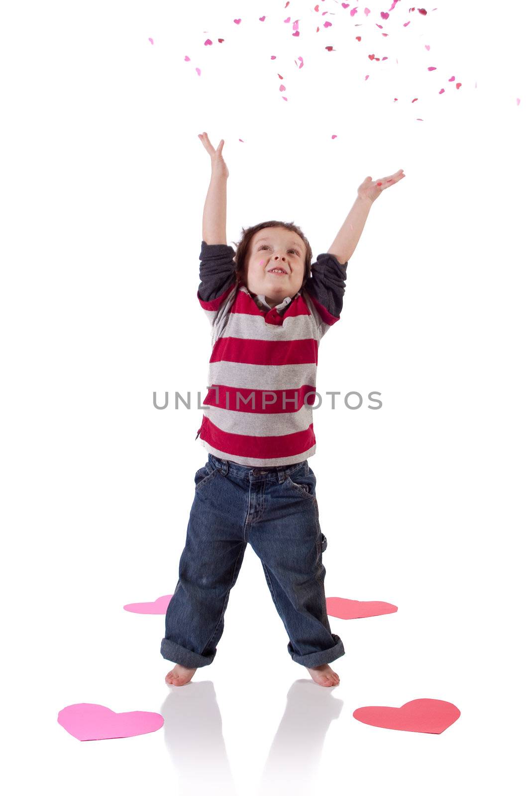 Cute little boy throwing heart shaped confetti in the air