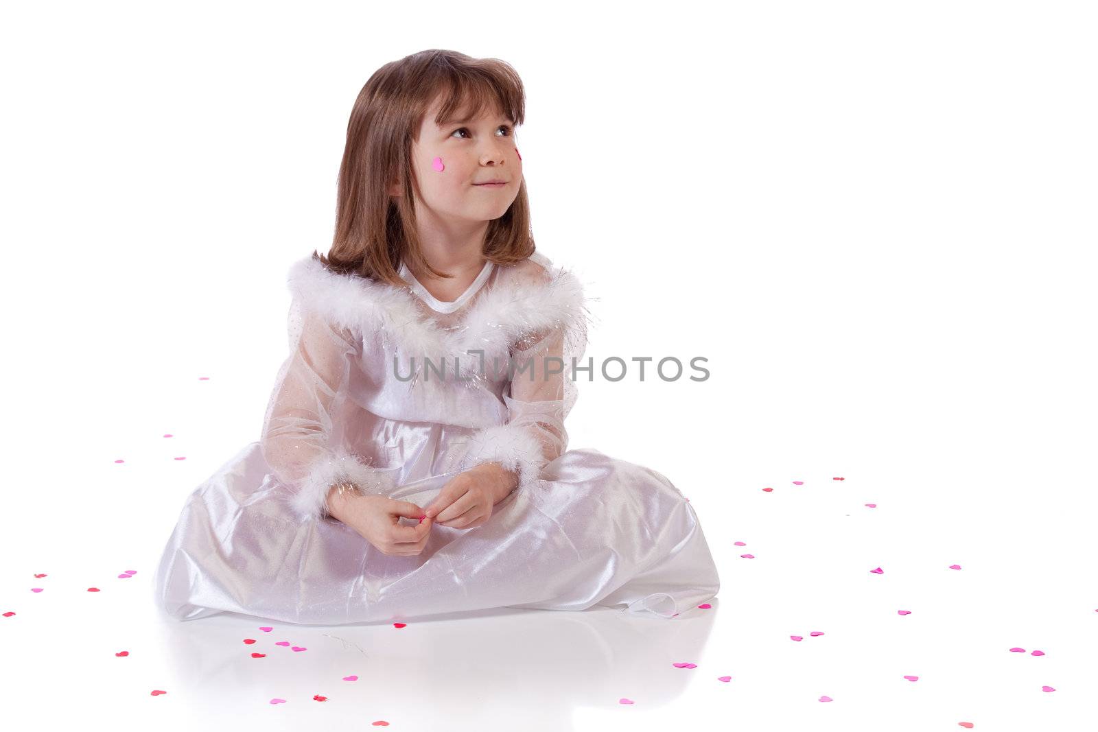 Cute little girl sitting on the floor with heart shaped confetti