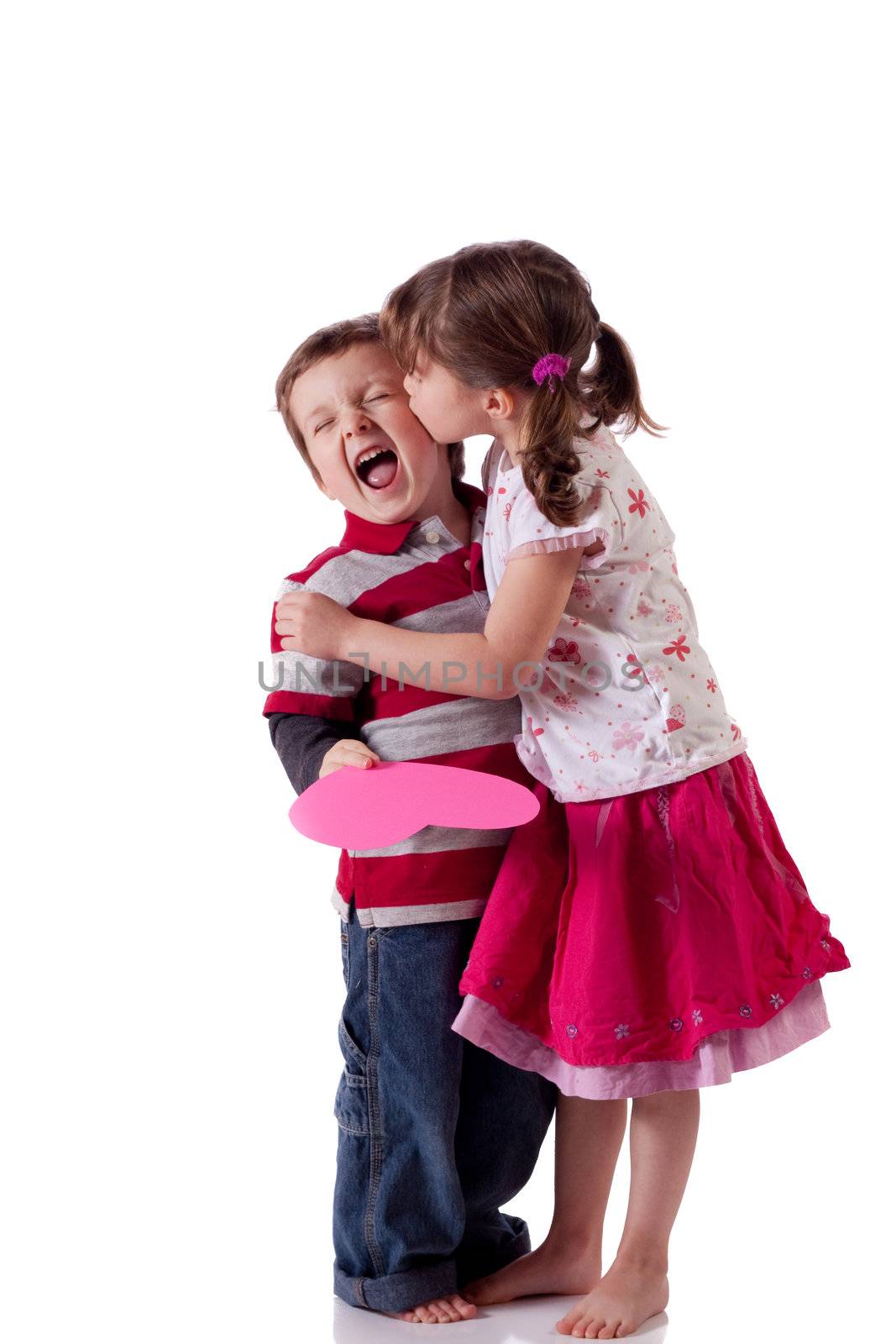 Cute little girl kissing a boy holding a pink heart